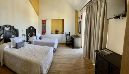 Habitación de hotel con 2 camas y TV de pantalla plana. en Marisol Hotel Boutique en San José del Cabo