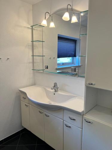 a white bathroom with a sink and a mirror at Fred og Ro Ferielejlighed in Ulstrup