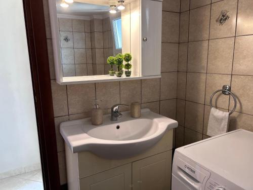 een badkamer met een wastafel en een spiegel bij Apartment on main pedestrian street with view in Nea Kalikratia