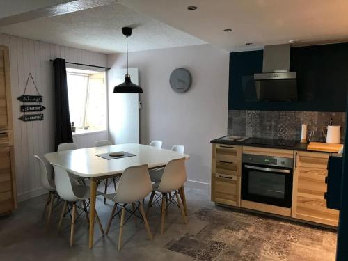 - une cuisine avec une table blanche et des chaises blanches dans l'établissement Appartement spacieux au cœur du massif du Sancy, à Le Mont-Dore