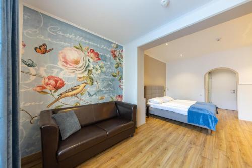 多瑙河畔克雷姆斯的住宿－菩提樹大道酒店，一间带沙发和花卉壁画墙的卧室