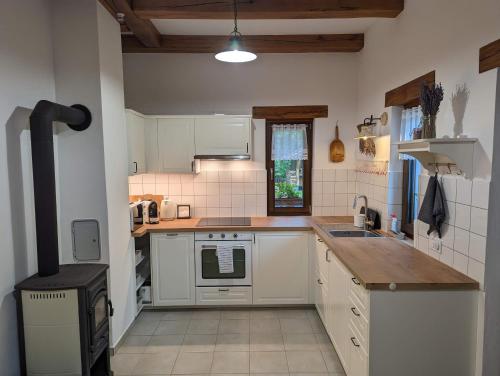 a kitchen with white cabinets and a stove at Kosbor Vendégház in Monoszló