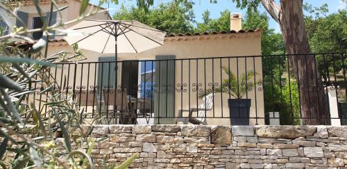 a fence with an umbrella and a stone wall at Une maison en Provence in Pierrevert