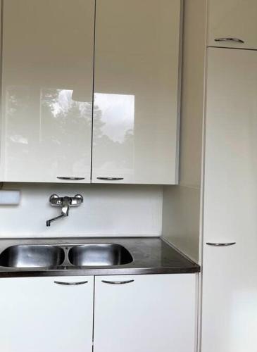 eine weiße Küche mit einem Waschbecken und weißen Schränken in der Unterkunft Studio next to metrostation in Espoo