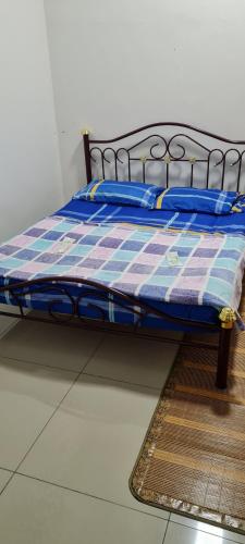 a bed with a checkered blanket sitting on the floor at DHut Homestay puncak iskandar in Seri Iskandar