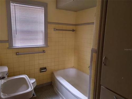 a bathroom with a tub and a sink and a toilet at Mid Century Style Cottage Near Historic Downtown in Eustis