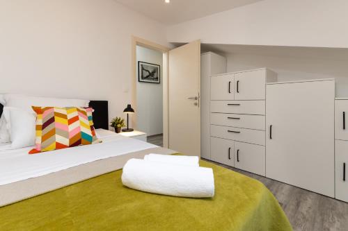 een slaapkamer met een wit bed en een gele deken bij Olivae Apartments in Trogir