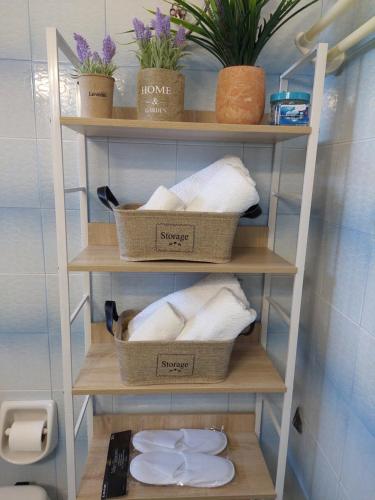 een plank met drie manden handdoeken in een badkamer bij Eva's apartment in Karistos