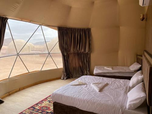 a room with two beds and a large window at Al Rifi Luxury Camp in Wadi Rum