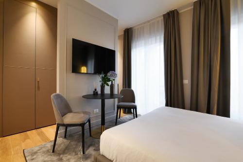 a hotel room with a bed and a table and chairs at PRESTIGE BOUTIQUE APARTHOTEL - Piazza Duomo View in Milan