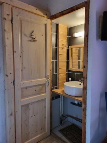 a bathroom with a sink and a mirror and a door at Auberge La Coulette in Vars