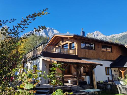a large wooden house with mountains in the background at AlpinCreek in Leogang