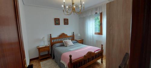 Habitación pequeña con cama y lámpara de araña. en Apartamento Sobrevilla SDR IV, en Santander