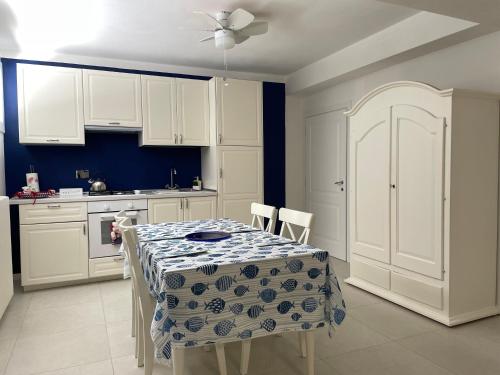 una cucina con tavolo, armadi bianchi e pareti blu di Casa Morandi MARE a San Vincenzo