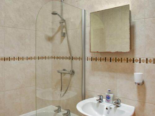 a bathroom with a shower and a sink and a mirror at Hatters Croft in Cockermouth