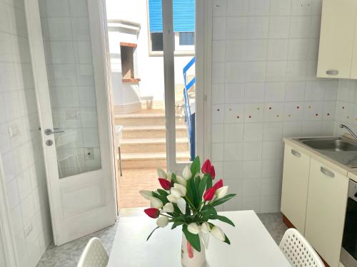 una cocina con una mesa con un jarrón de flores. en Villa Azzurra, en Marina di Mancaversa