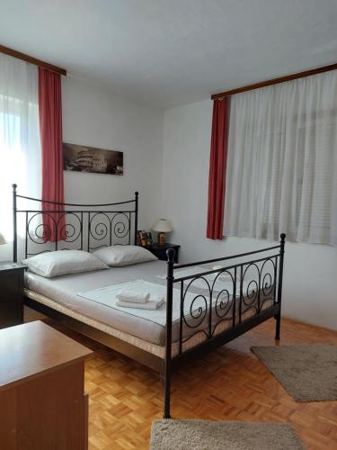 a bedroom with a black bed with red curtains at Orange city apartment's Repić in Biograd na Moru