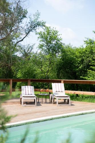 two chairs sitting on a deck next to a pool at Le Moulin du Porteil in Campagne