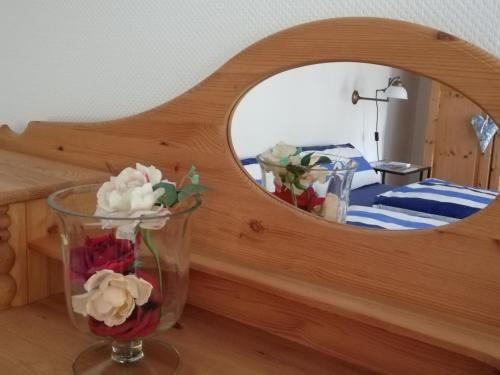 a vase of flowers on a table in front of a mirror at Hyggelig in Kosel