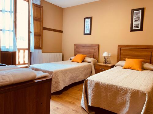 um quarto com 2 camas com almofadas laranja em Hostal La Serna em Potes
