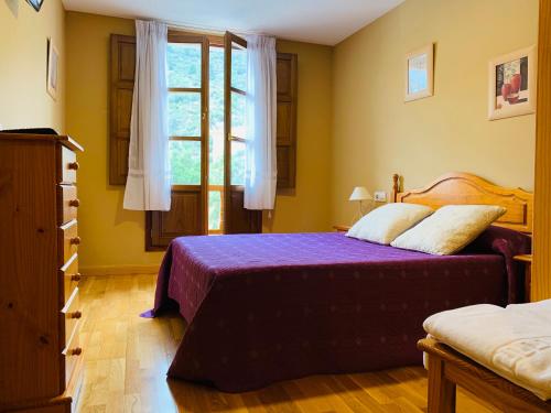 um quarto com uma cama com lençóis roxos e uma janela em Hostal La Serna em Potes