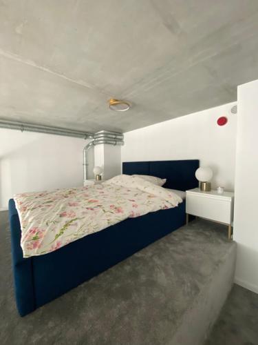Apartament Wrocław-Lotnisko في فروتسواف: غرفة نوم بسرير ازرق وجدار ابيض