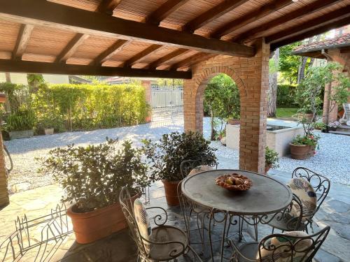 a patio with a table and chairs under a wooden roof at Villa Vanna - the ancient Forte just in the center in Forte dei Marmi