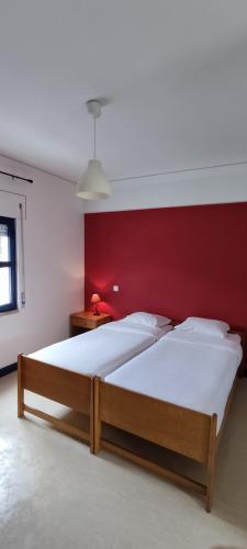 a bedroom with a large bed with a red wall at HI Ovar - Pousada de Juventude in Ovar