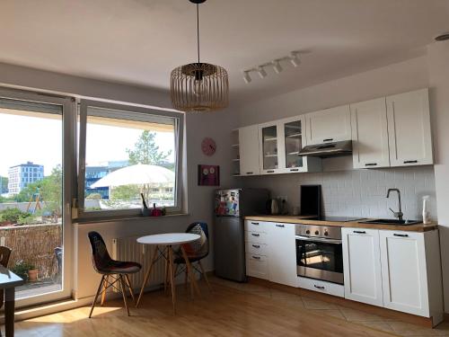 kuchnia z białymi szafkami oraz stołem i krzesłami w obiekcie Bałtycki Chill - apartament z możliwością Home Office w mieście Gdynia