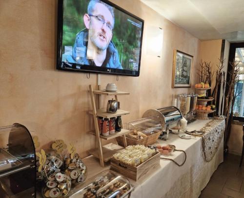 un televisore appeso a un muro con un tavolo con cibo di Hotel Bel Sogno a Rimini