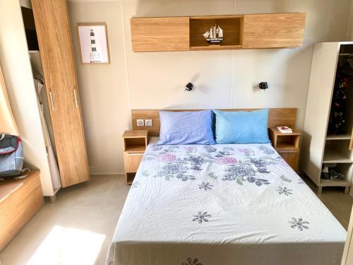 a bedroom with a bed with blue pillows at Mobil Home excellence 6 personnes au camping Mer et Soleil, Saint George d'Oléron in Les Sables Vignier