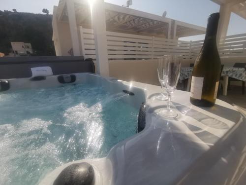 a hot tub with a bottle of wine and a glass at MARE e Terra Holiday fronte mare in San Vito lo Capo