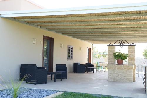 a patio with chairs and tables and a wooden ceiling at le casette in Aradeo