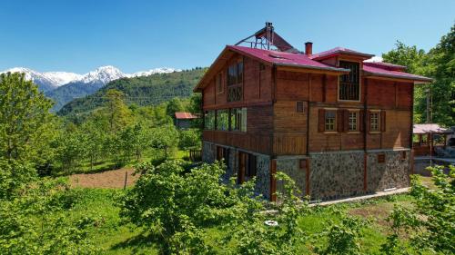 ein großes Holzhaus mit Bergen im Hintergrund in der Unterkunft Selin Yaşam Evi in Artvin