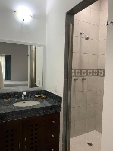 ein Badezimmer mit Waschbecken und Dusche mit Spiegel in der Unterkunft Almarea Vacation Condo in Playa del Carmen