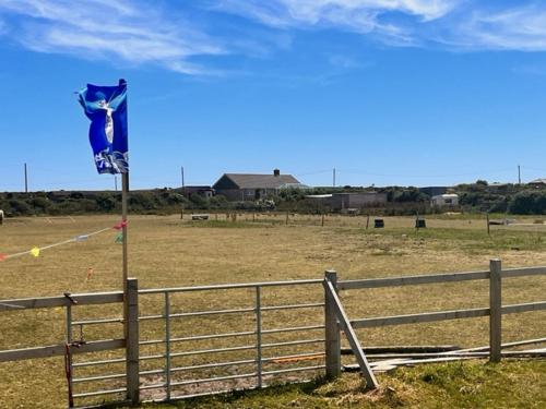 a blue flag in a field next to a fence at Sadies Sanctuary in St. Just