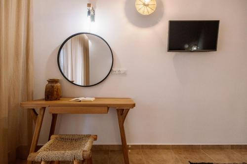a mirror on a wall next to a wooden table at Ariadne Hotel in Agios Prokopios