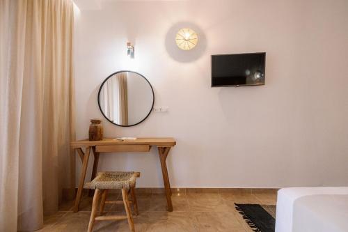 a room with a table and a mirror and a tv at Ariadne Hotel in Agios Prokopios