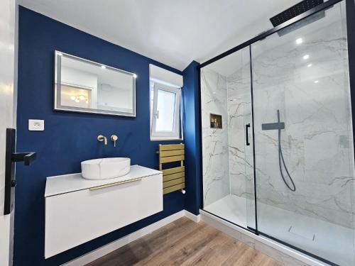 La salle de bains bleue est pourvue d'un lavabo et d'une douche. dans l'établissement Royal Terrace - Maison plage & Parking privé, à Dunkerque