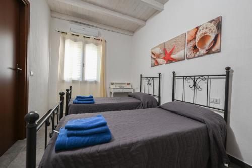 een slaapkamer met 3 bedden en blauwe dekens bij B&B Su Neulagi in Triei