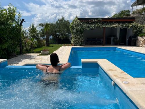 une femme est assise dans une piscine dans l'établissement Holiday House Vita, à Klis