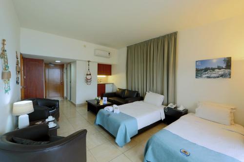 um quarto de hotel com duas camas e um sofá em Rabiya Marine Hotel em Ţabarjā