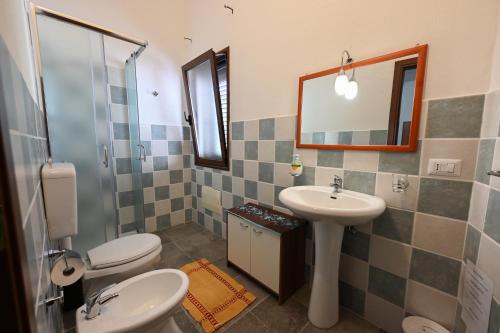 y baño con 2 aseos, lavamanos y espejo. en B&B Su Neulagi en Triei