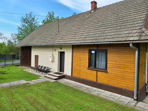 a wooden house with a patio and a yard at Domek nad Potokiem in Rzyki