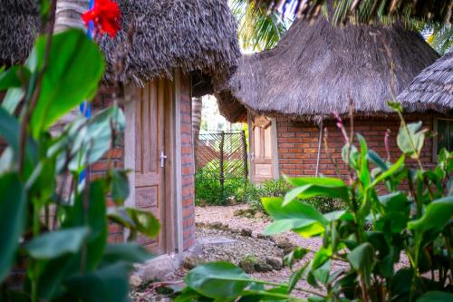 an open door to a building with a thatch roof at AFLII Guest house in Mtwara