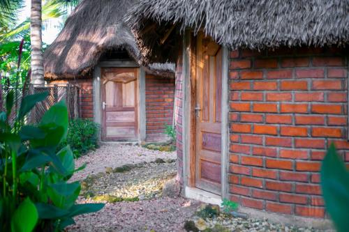 a brick building with a thatch roof and a door at AFLII Guest house in Mtwara