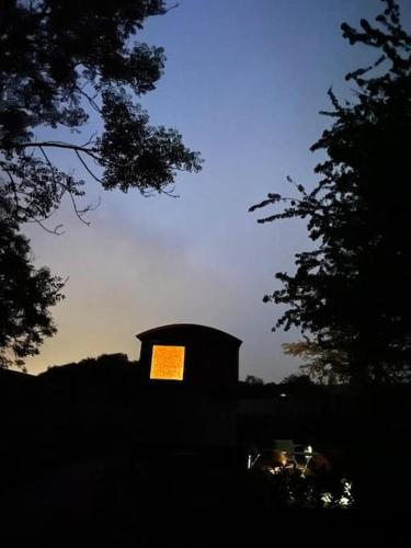 une tour d'horloge avec une lumière au coucher du soleil dans l'établissement The Rookery, à Lothersdale