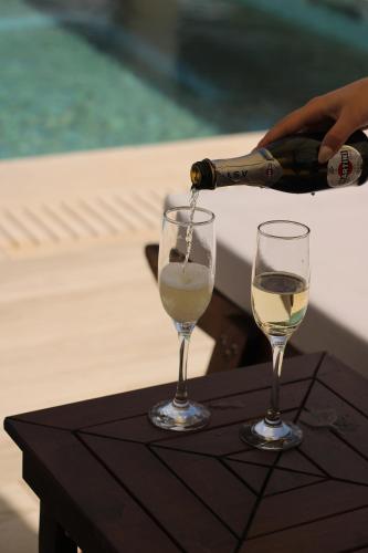 a person pouring a bottle of wine into two wine glasses at Villa Palma in Kallithea Halkidikis