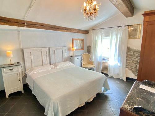 um quarto com uma grande cama branca e um lustre em AGRITURISMO CASA OLIVIERI em Sestri Levante