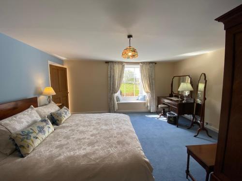 a bedroom with a bed and a desk and a window at North Farm in Hexham